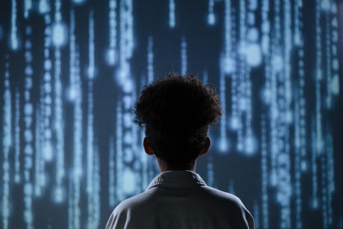 Ein junger Mann steht mit dem Gesicht vor einem Großen Computer-Code